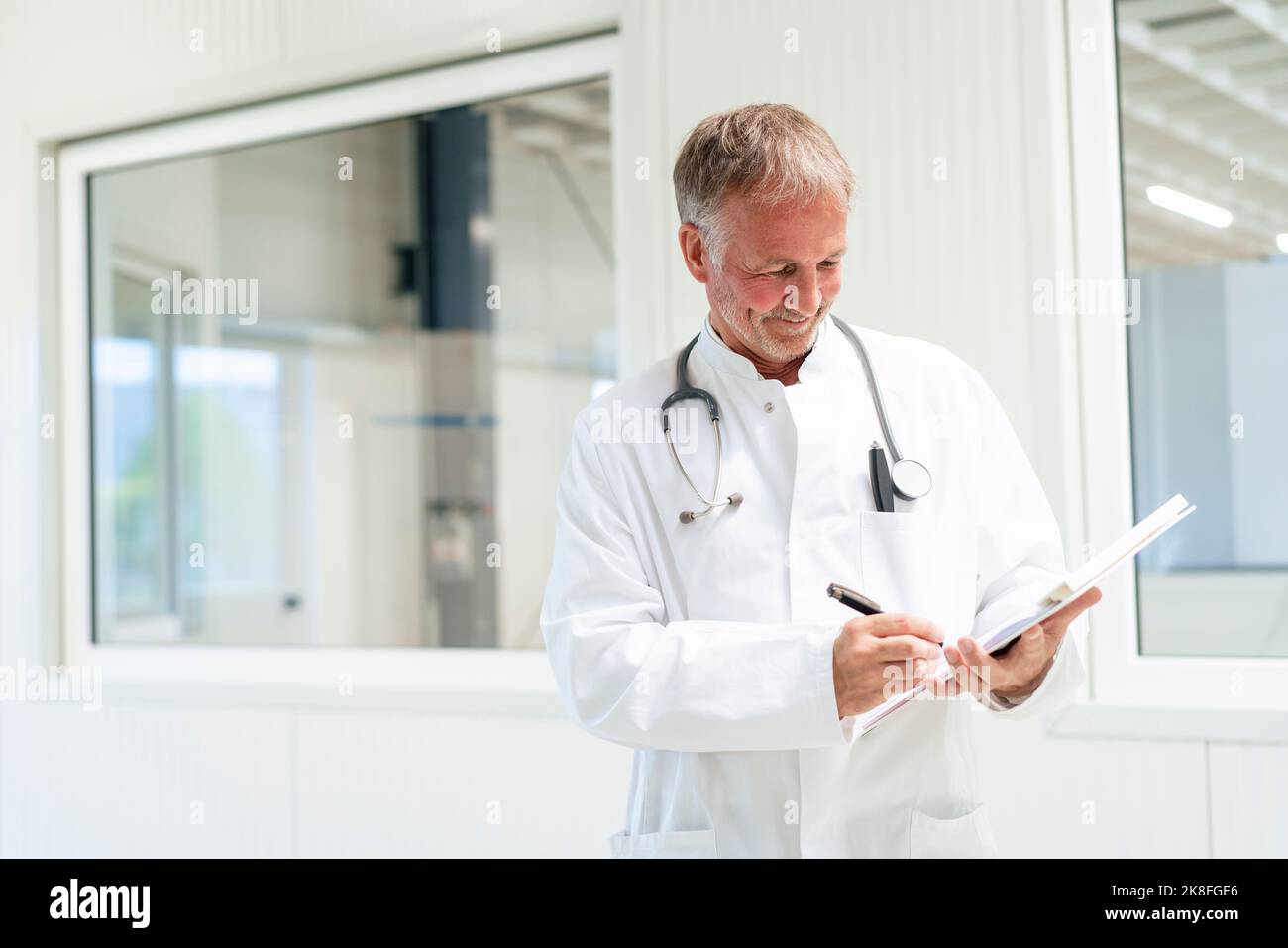 Smiling doctor writing on document at clinic Stock Photo