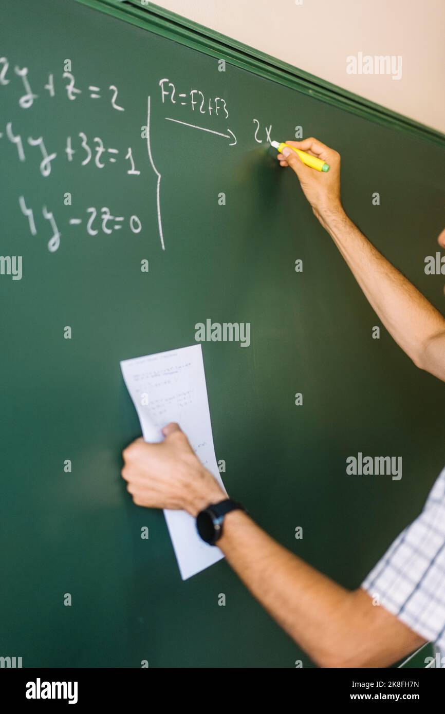 Math teacher writing on chalkboard in classroom Stock Photo Alamy