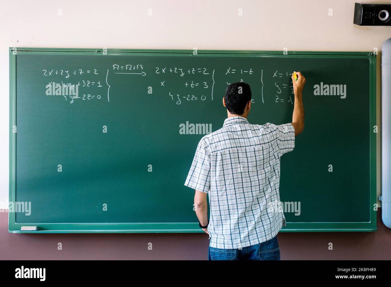 Math teacher writing formulas on chalkboard in classroom Stock Photo