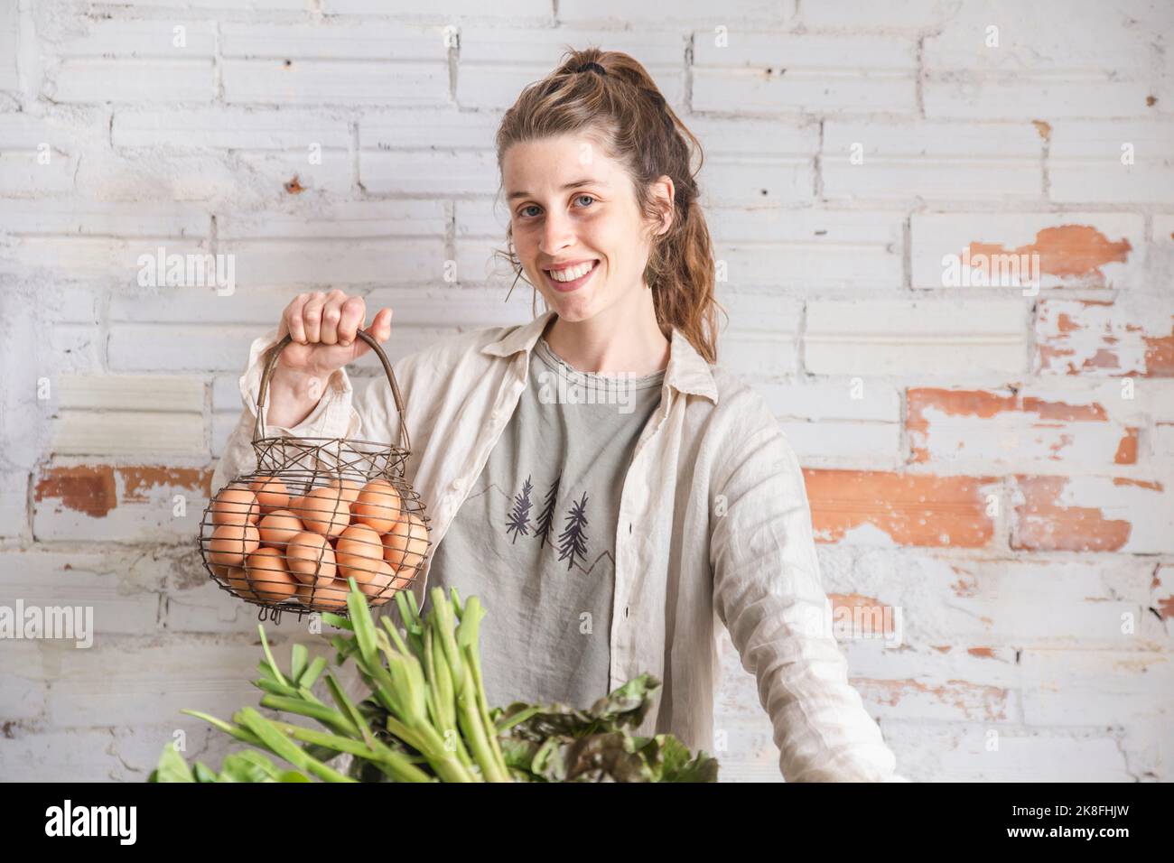 Happy grocer holding eggs in front of brick wall Stock Photo