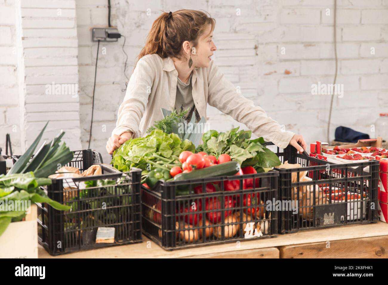 Owner leaning on vegetable crates at checkout counter in shop Stock
