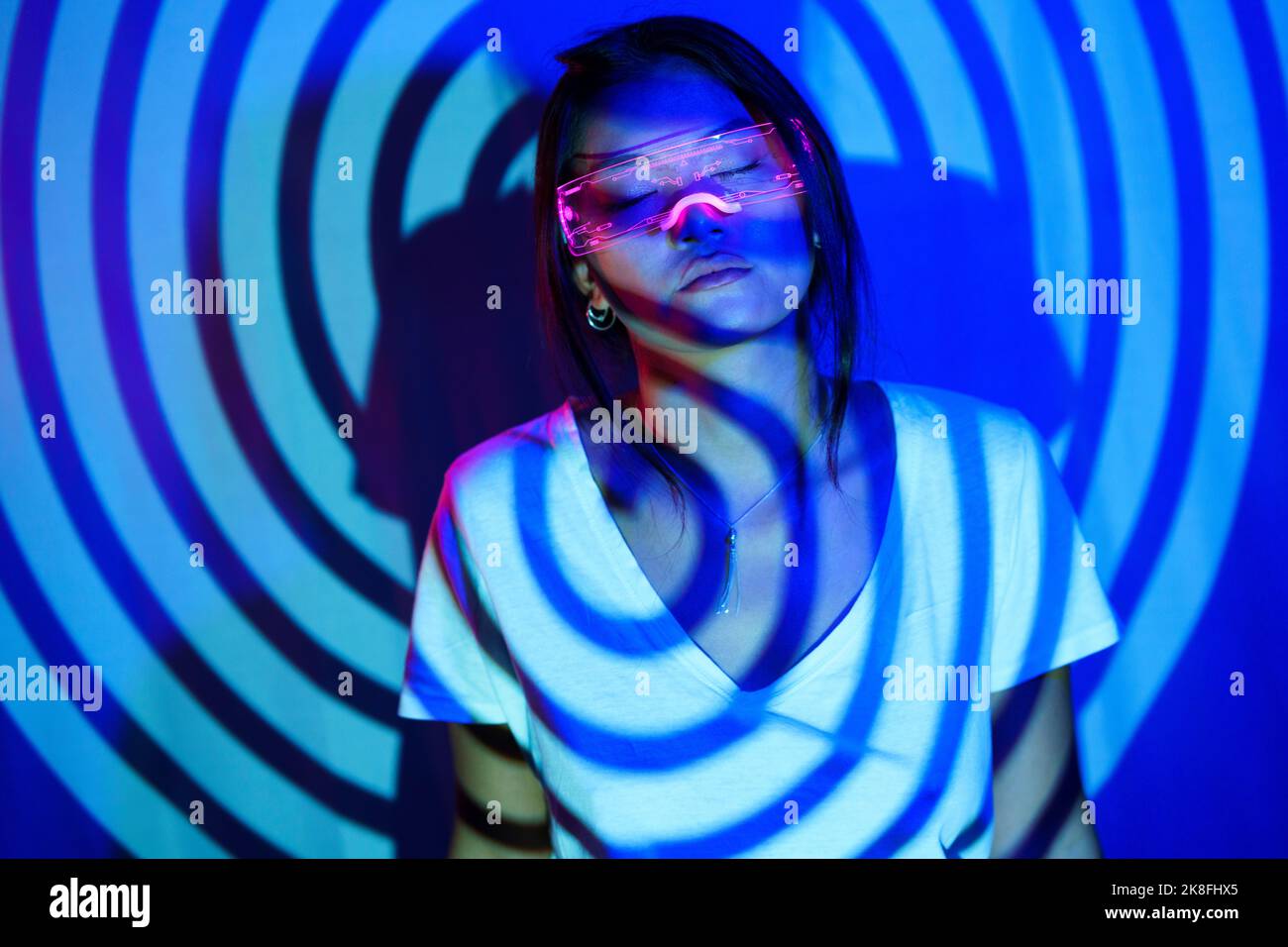 Spiral shadow on young woman wearing LED smart glasses Stock Photo