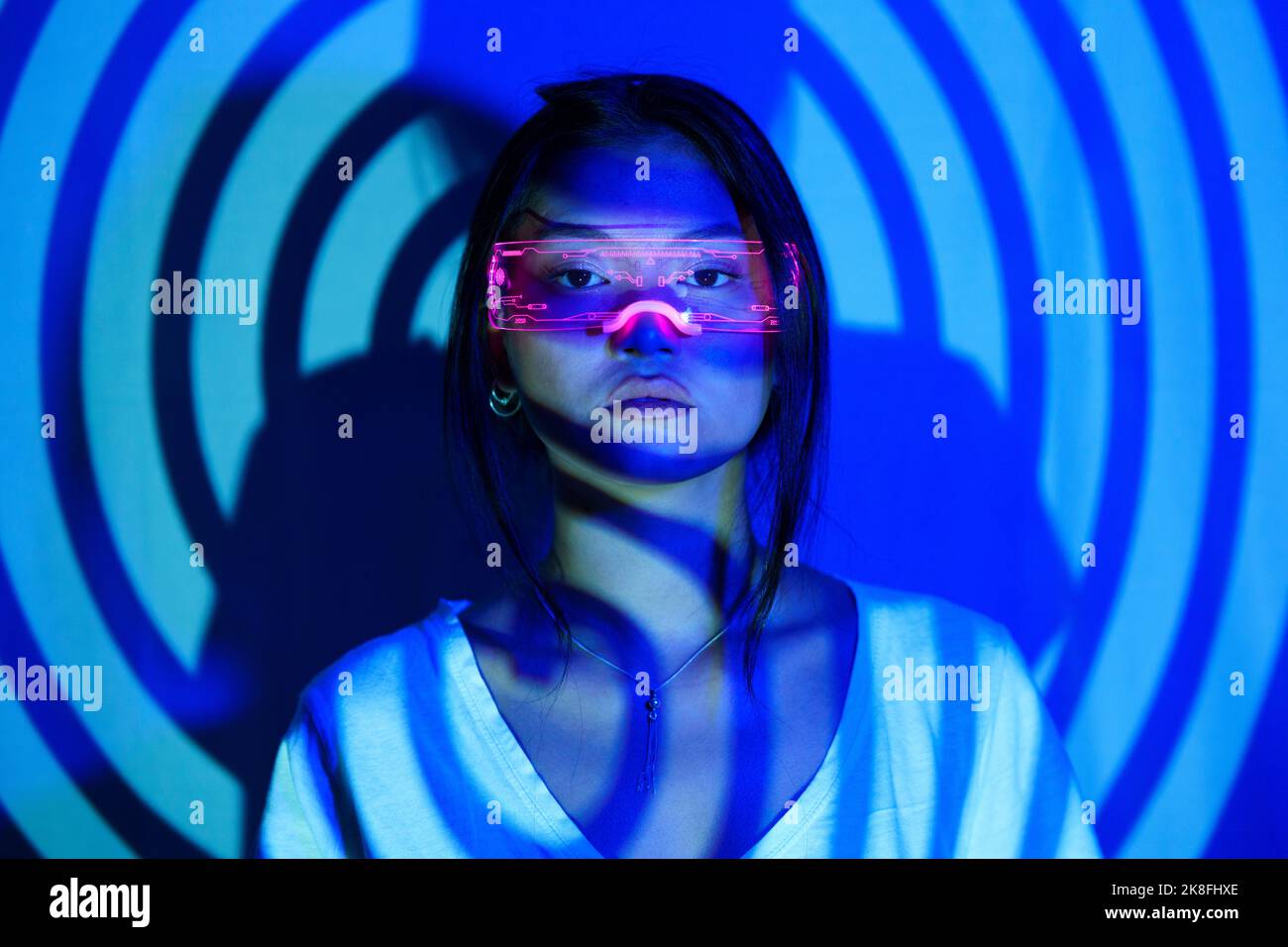 Spiral shadow on young woman wearing LED futuristic glasses Stock Photo