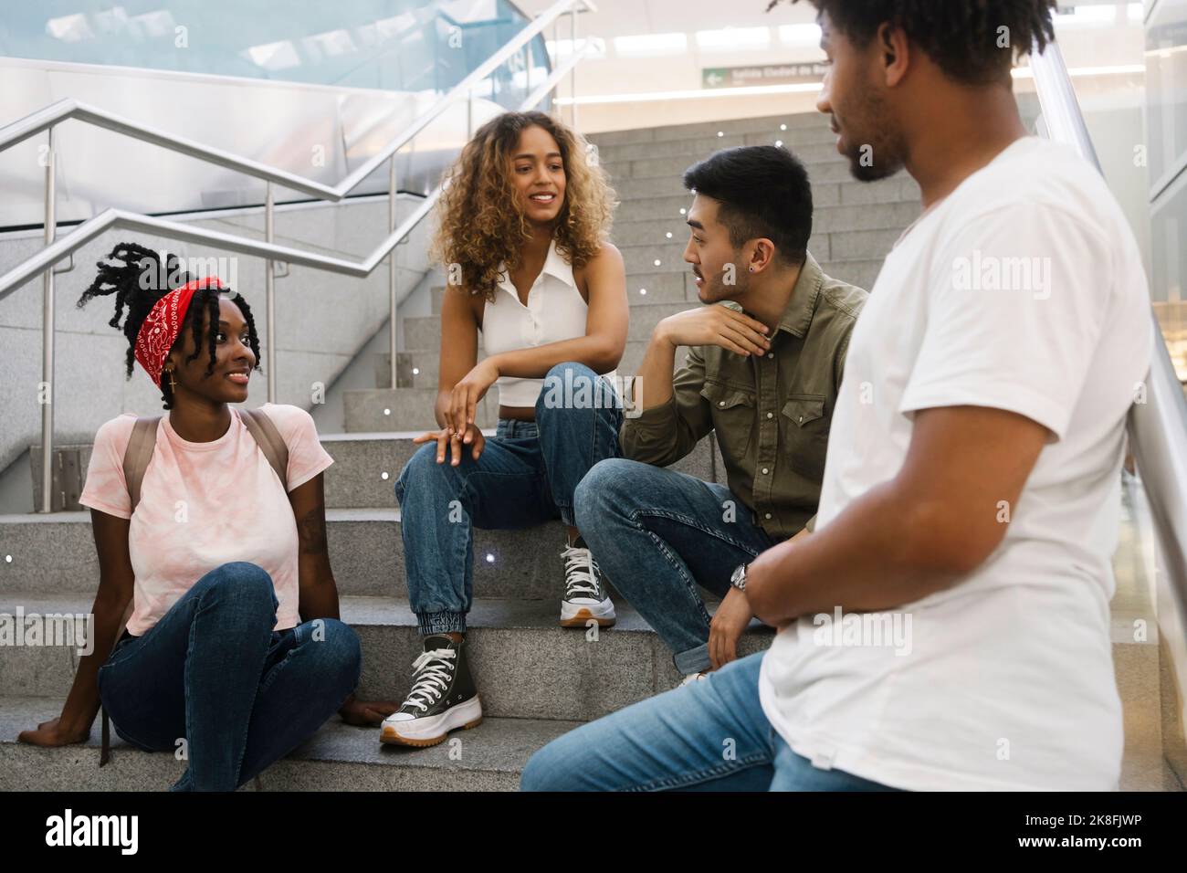 Young man talking to multiracial friends on staircase Stock Photo