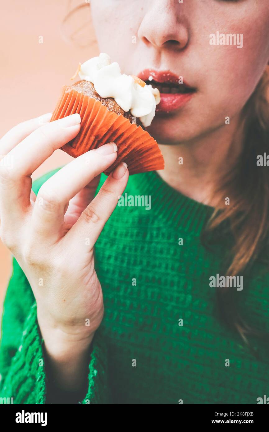 Woman eating cupcake with icing Stock Photo