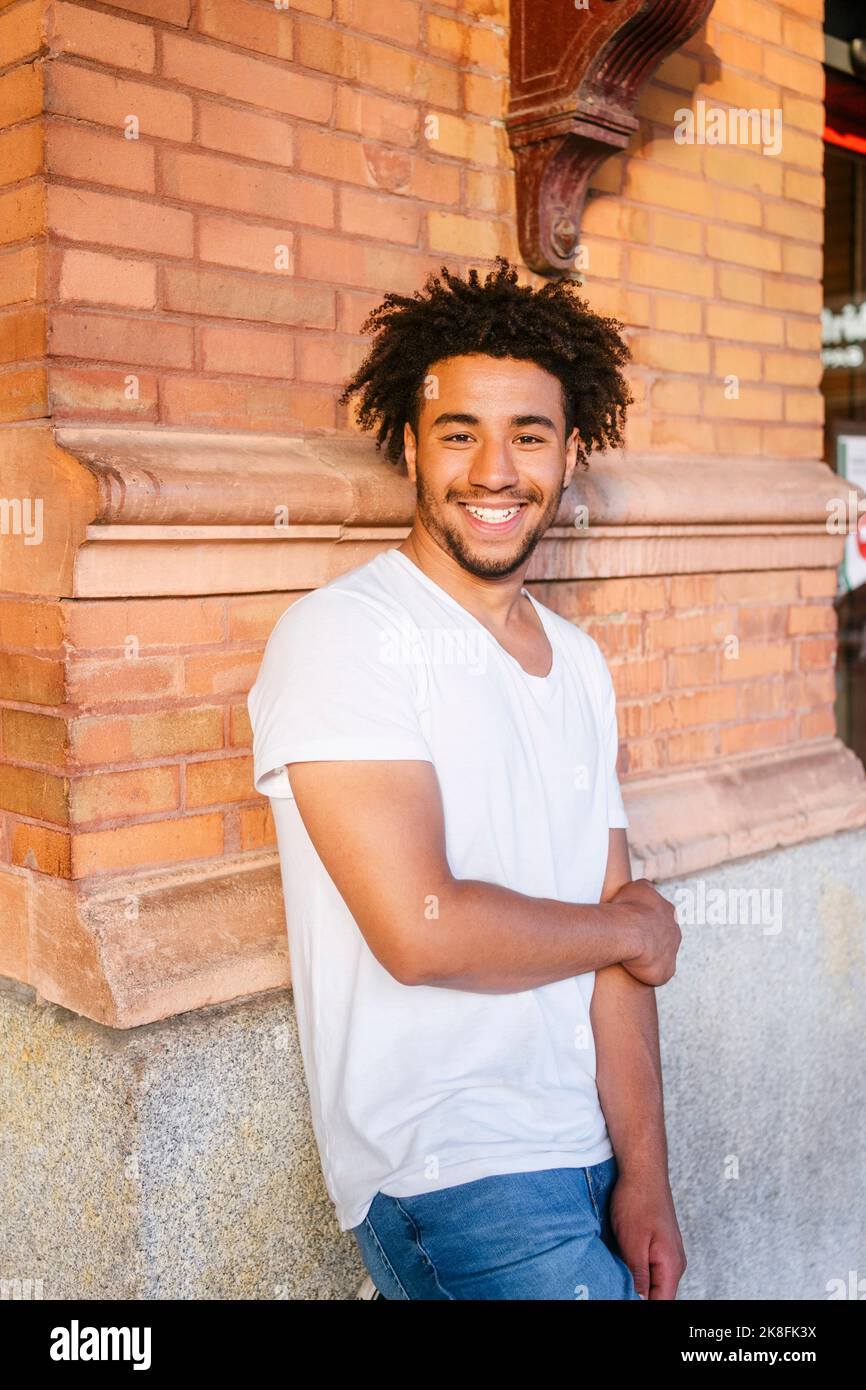 Smiling young man leaning on wall Stock Photo