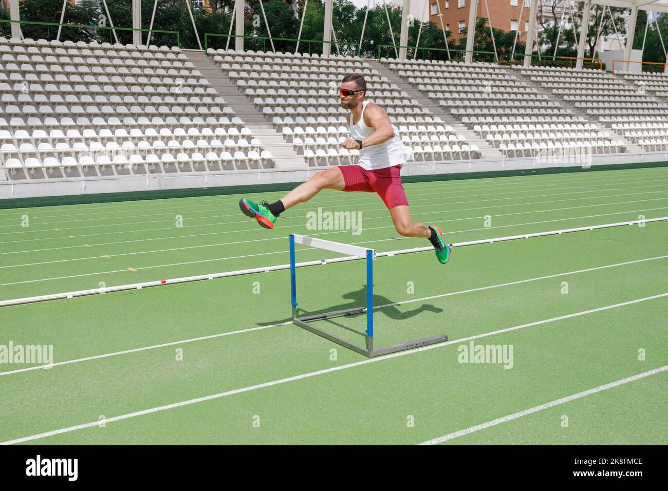 Athlete jumping over hurdle on sports track Stock Photo Alamy