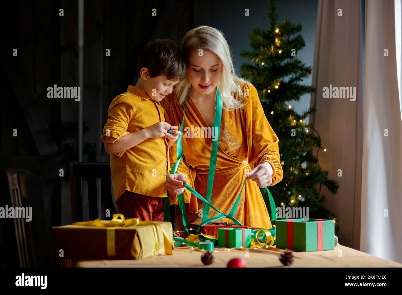 Woman showing son how to tie bow on present Stock Photo