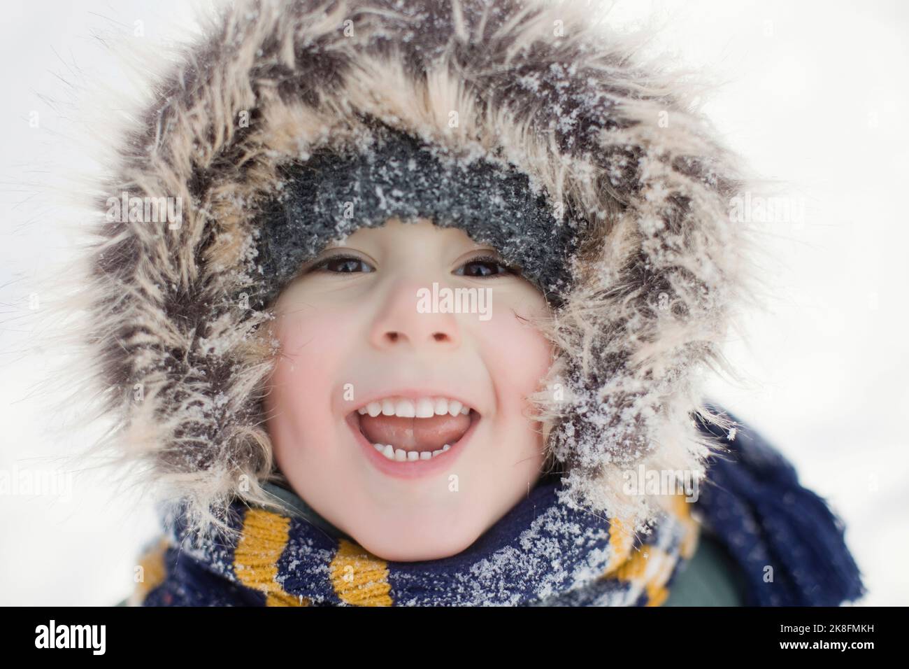 Cute boy with fur hood lauging in winter Stock Photo
