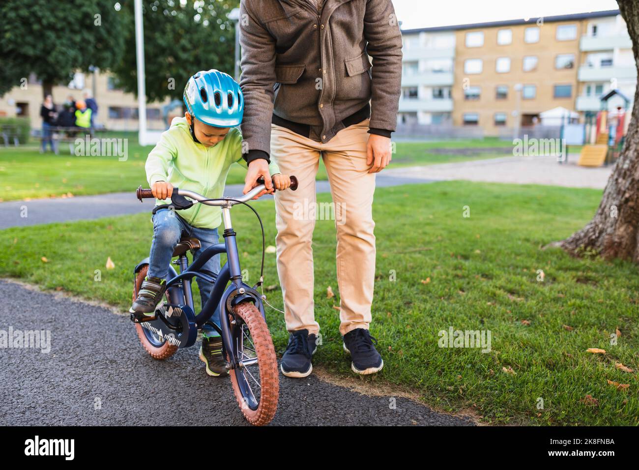 Father teaching son to ride bicycle on road Stock Photo