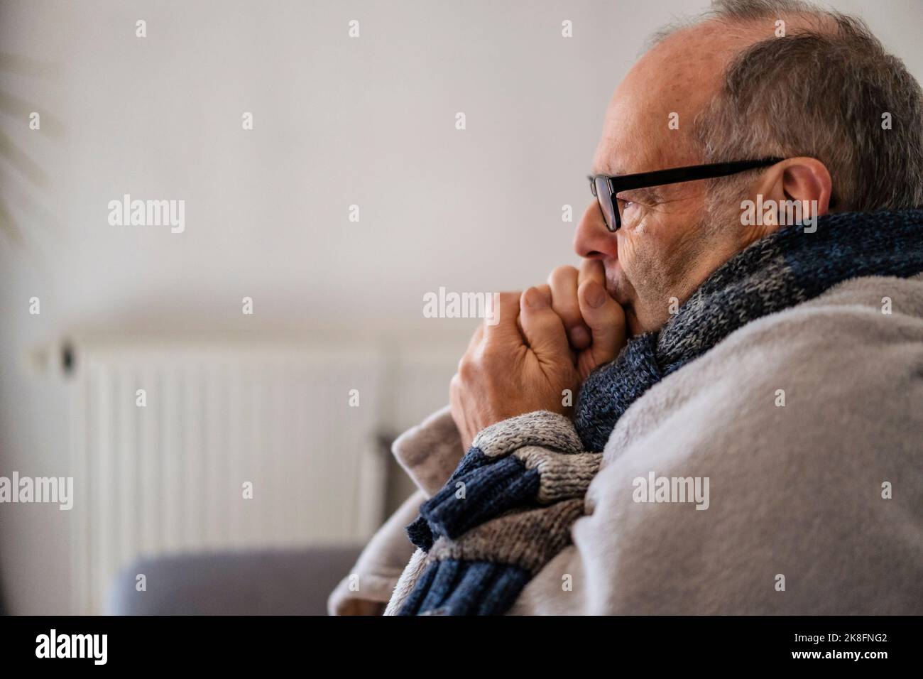Senior man wrapped in blanket feeling cold at home Stock Photo Alamy
