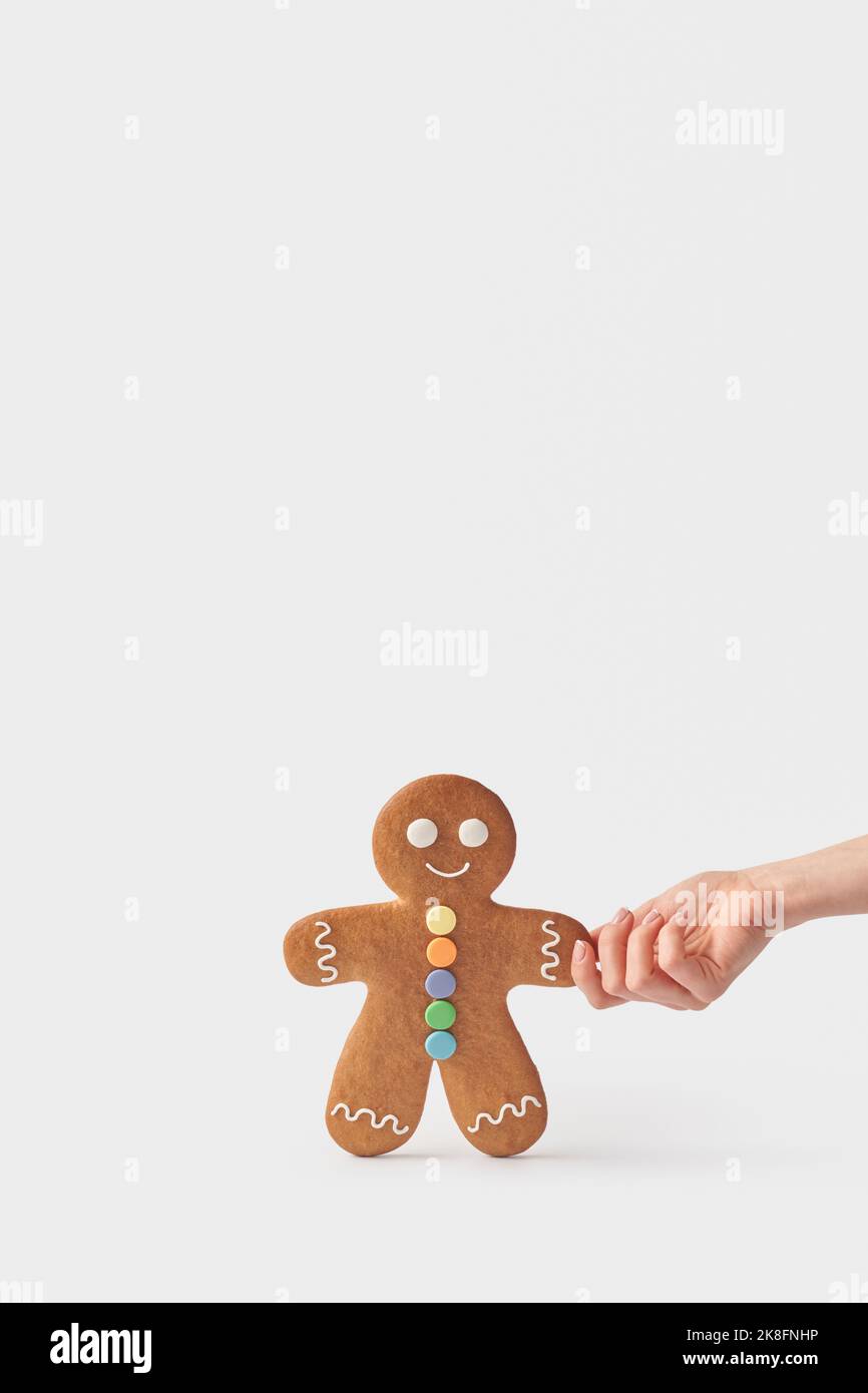 Hand of woman holding freshly backed gingerbread cookie against white background Stock Photo