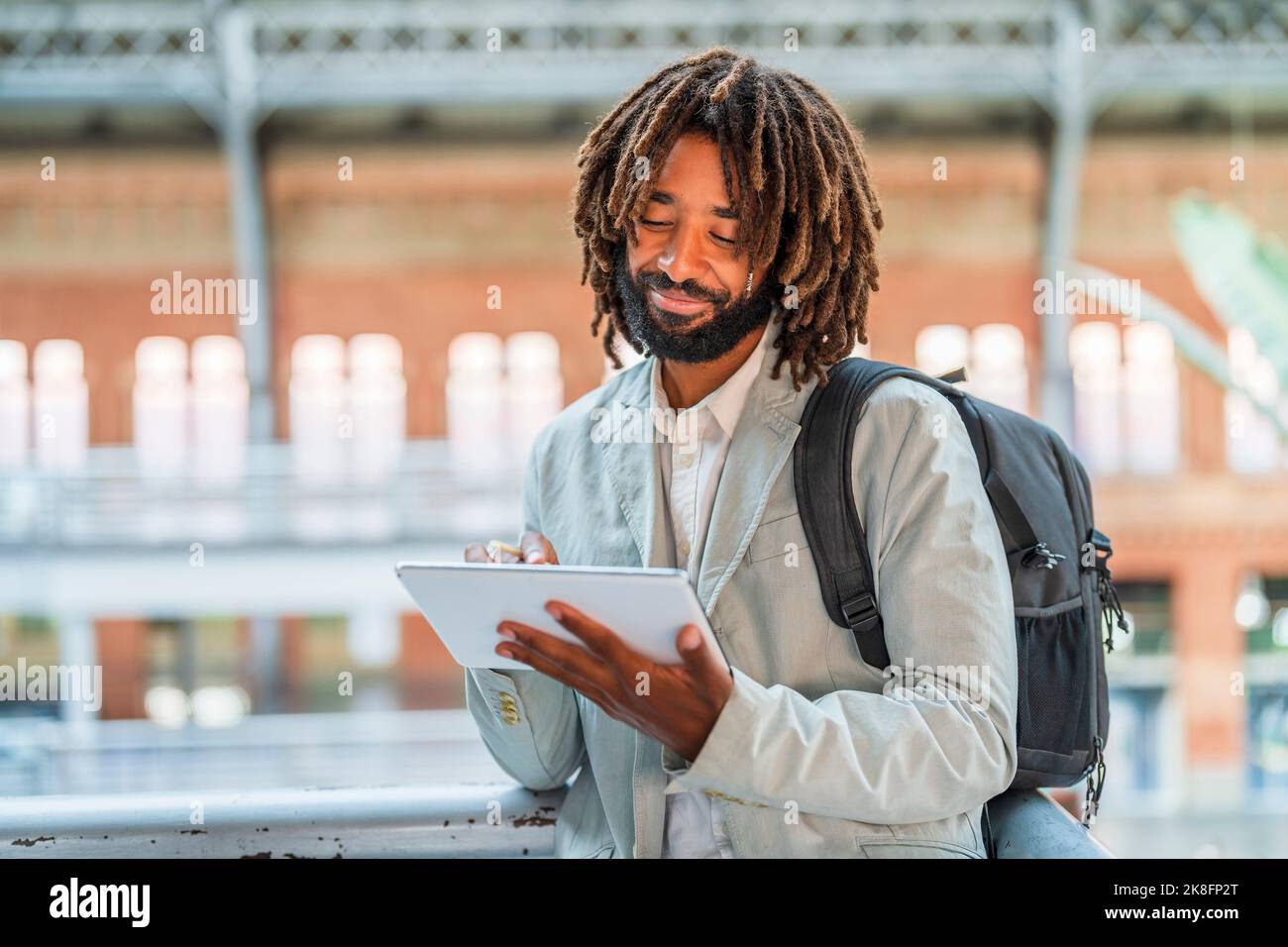 Smiling businessman using tablet PC at central station Stock Photo