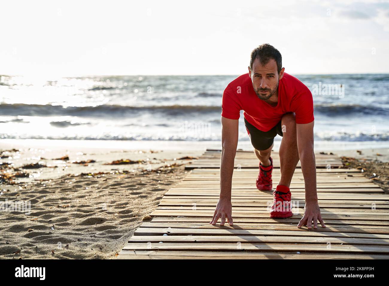 Man doing stretching exercise on boardwalk Stock Photo