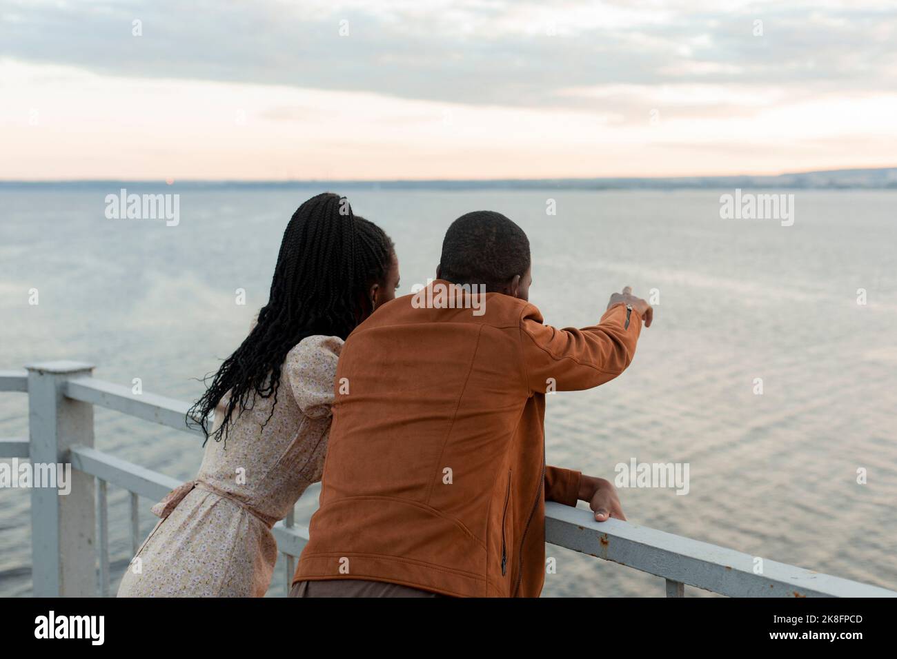 Young couple standing by railing looking at river Stock Photo