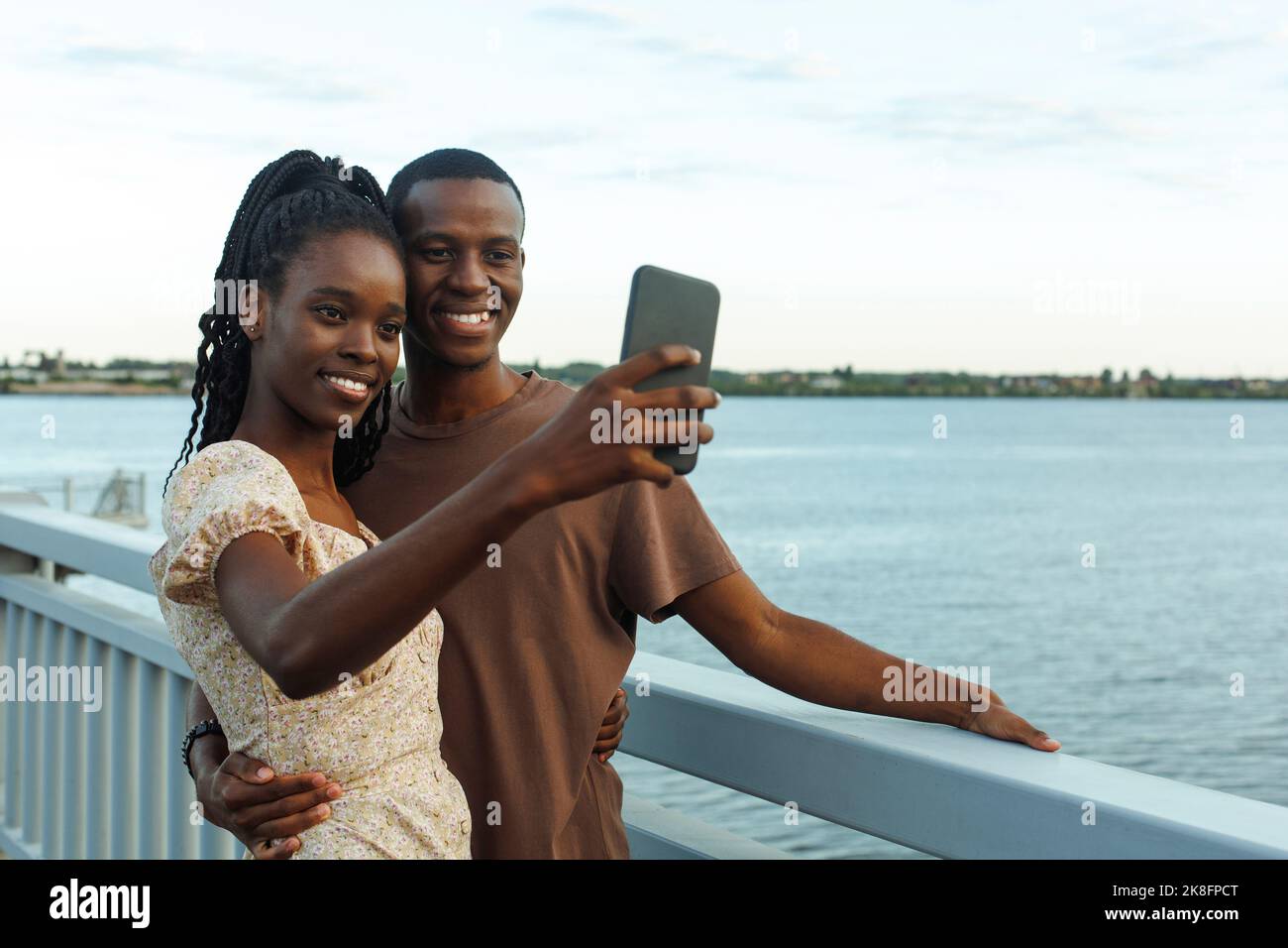 Smiling young couple taking selfie standing by river Stock Photo