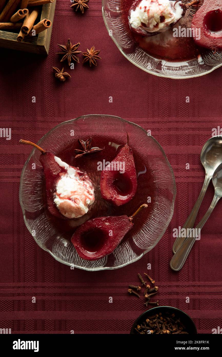 Servings of red wine spiced poached pears topped with vanilla ice cream