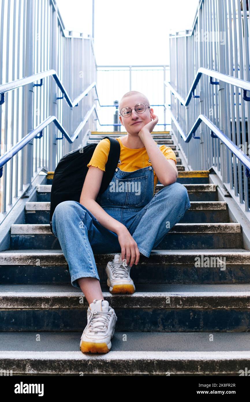 Androgynous person with backpack sitting on staircase Stock Photo