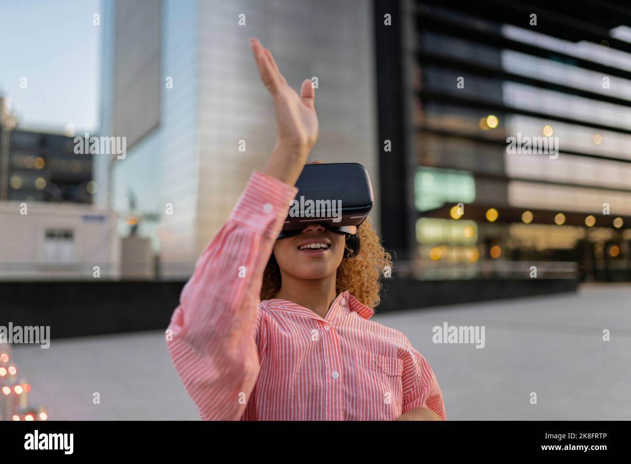 Smiling woman gesturing and using virtual reality simulator Stock Photo