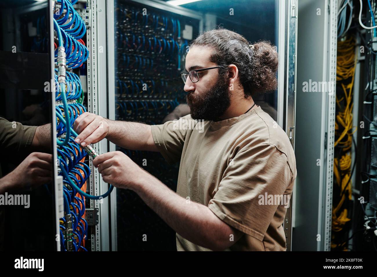 IT expert connecting computer cables in server room Stock Photo