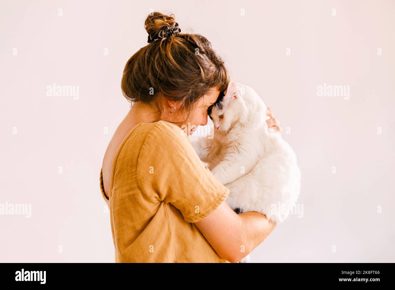 Woman playing with cat in front of wall at home Stock Photo