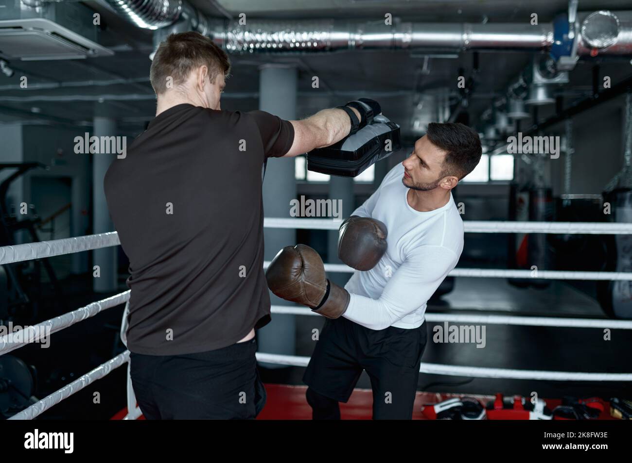 Two sparring partners in boxing gloves practice kicks Stock Photo