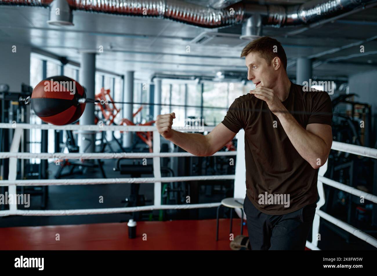 Young boxer trains with punching bag in gym Stock Photo