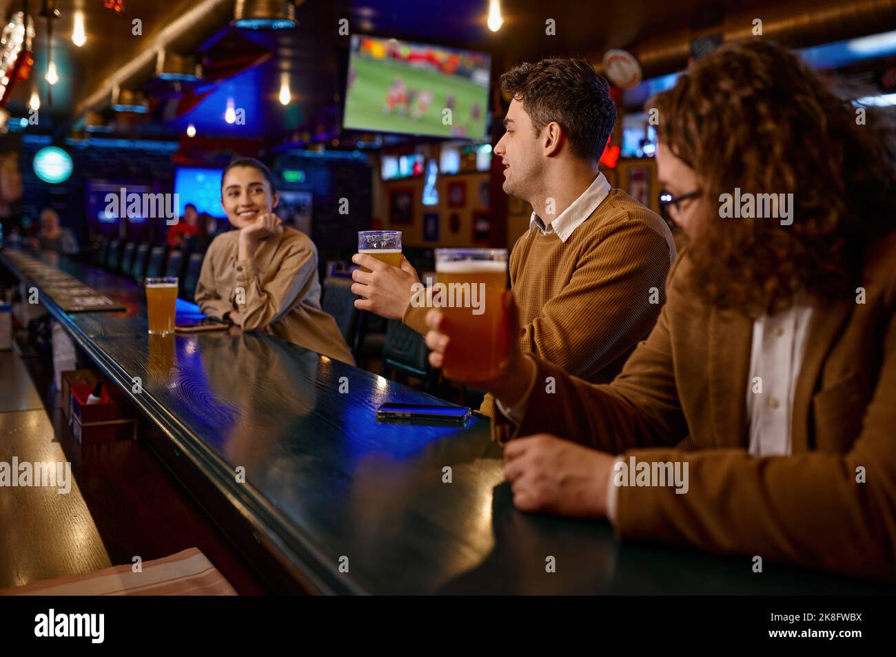 Young male friends flirting with woman at bar counter Stock Photo