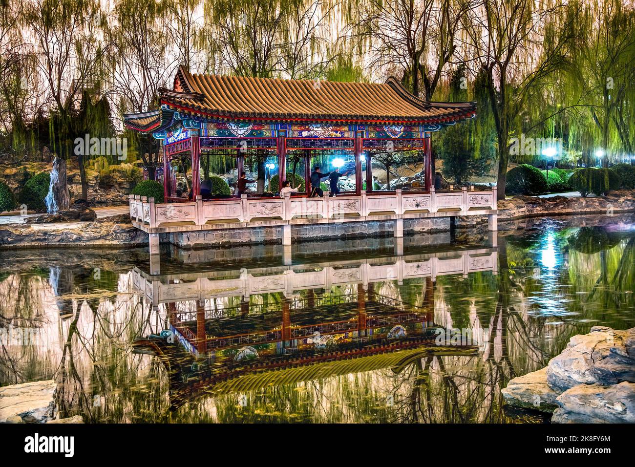 Wushu in Park Practicing Tai Chi Temple of Sun Pavilion Pond Reflection Green Willows Beijing China Stock Photo