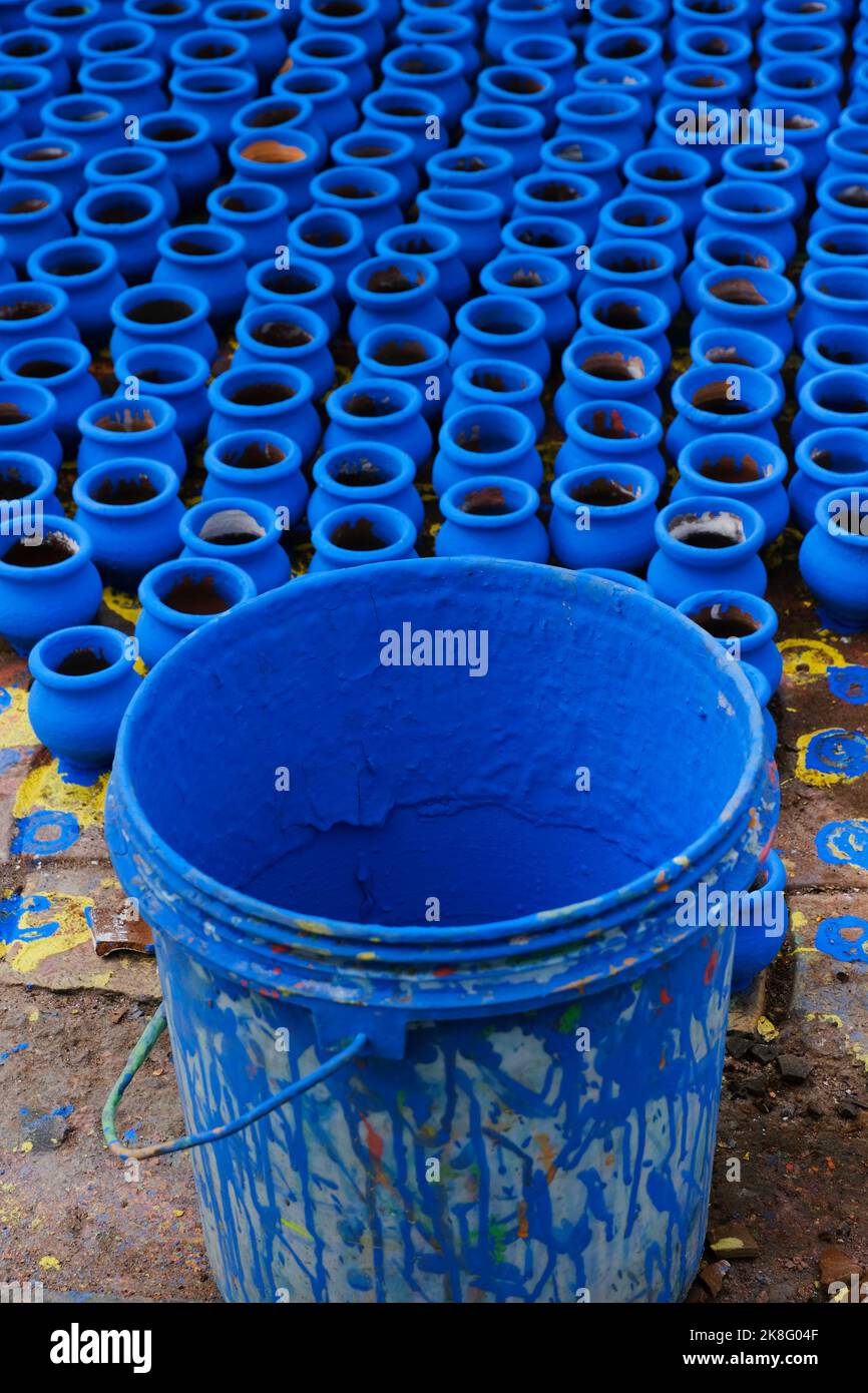 Artisan painting earthen pots, A background of colorful pots used for rituals during Diwali
