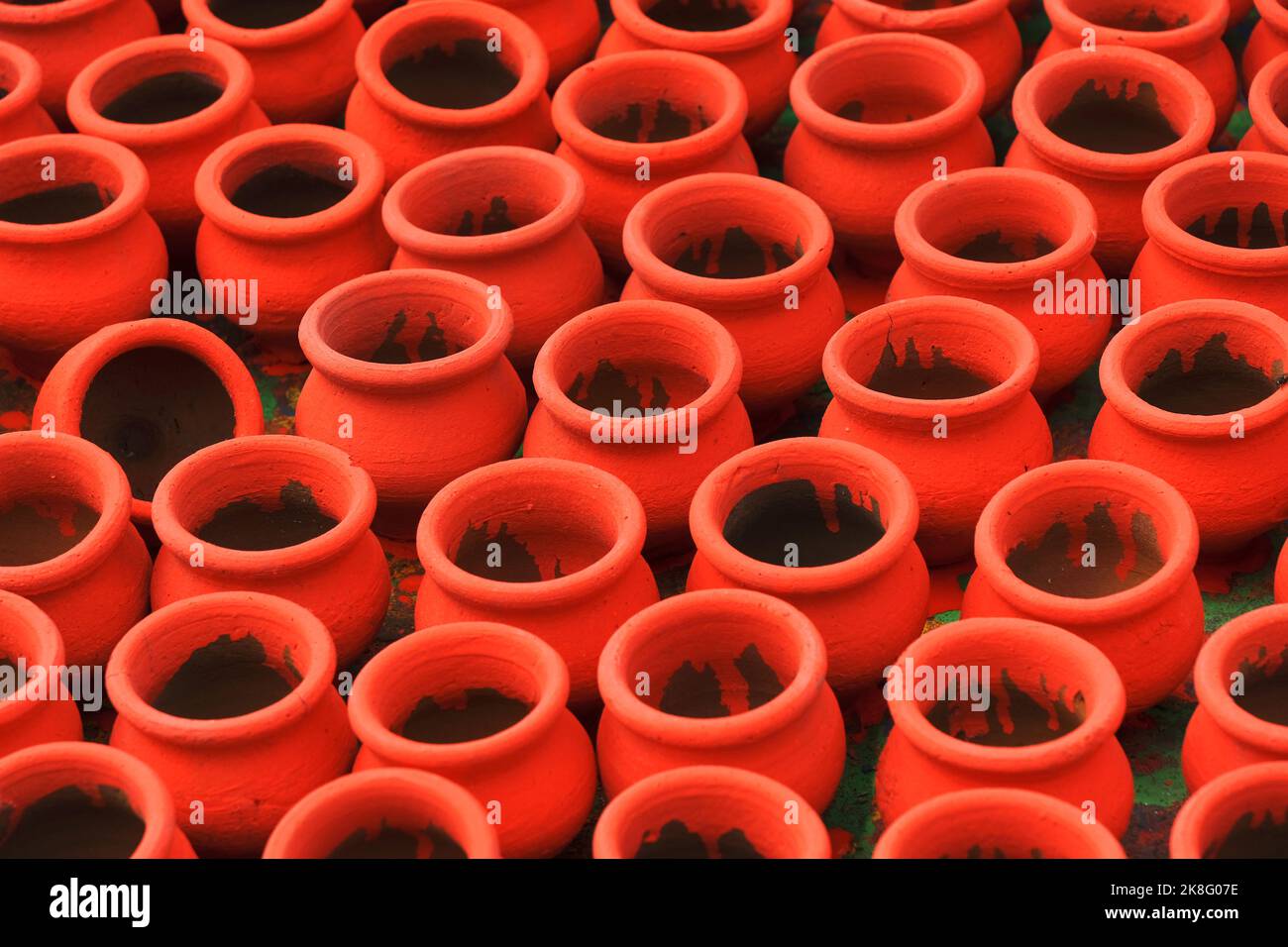 Artisan painting earthen pots, A background of colorful pots used for rituals during Diwali