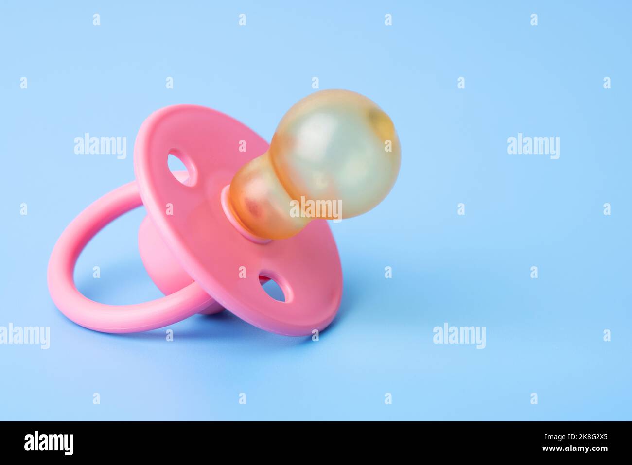 Orthodontic pacifier on a blue background. Pink baby pacifier Stock