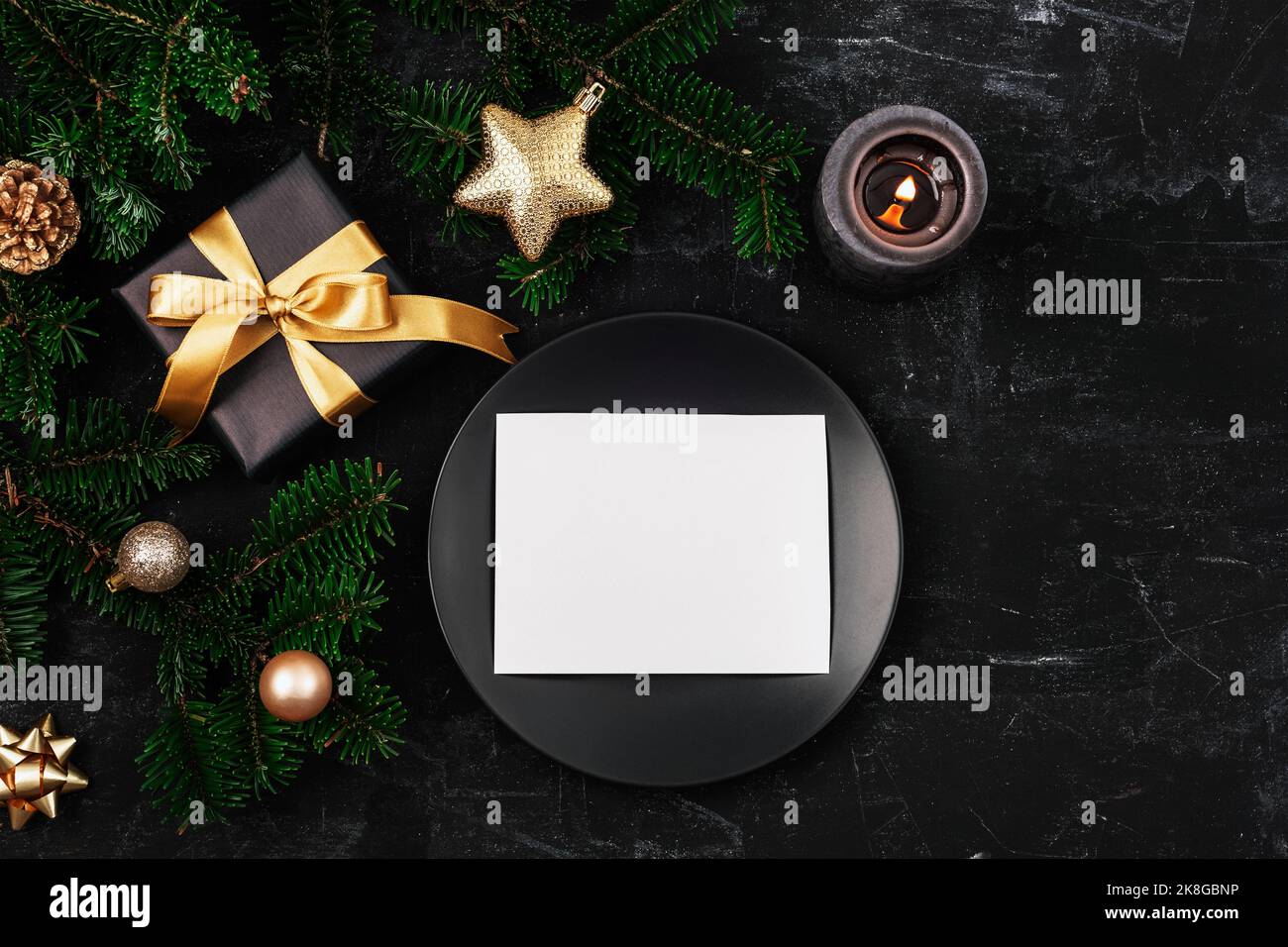 Stylish table setting, gift box, fir branches, star and balls, black