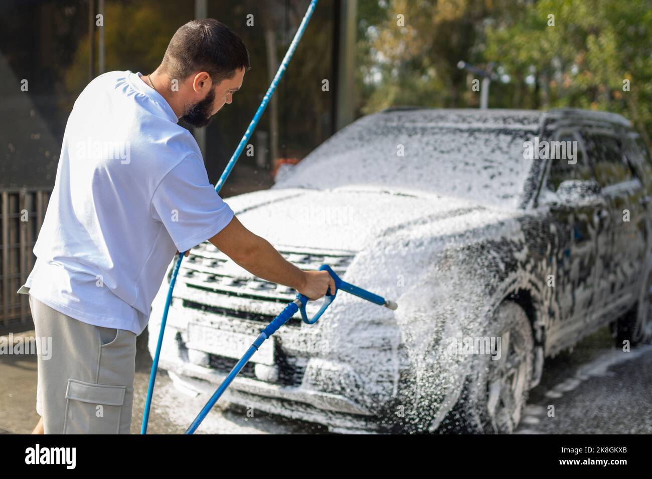 man washing a car in a selfservice car wash station with wahing foam