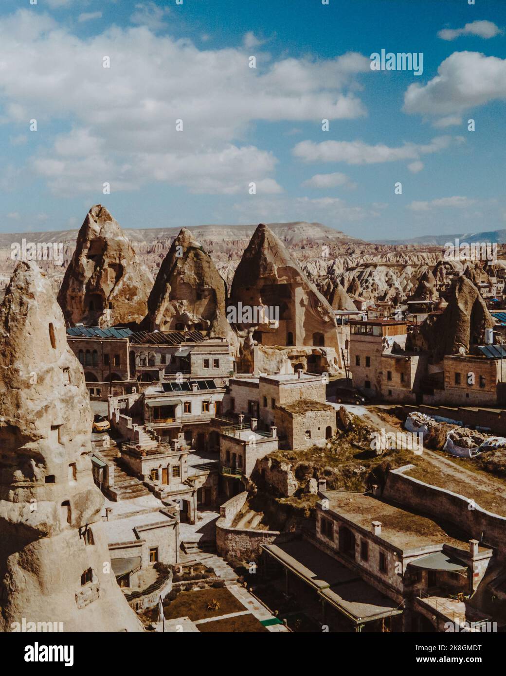Amazing scenery of massive fairy chimneys and traditional aged houses located in mountainous valley against cloudy blue sky on sunny day in Cappadocia Stock Photo