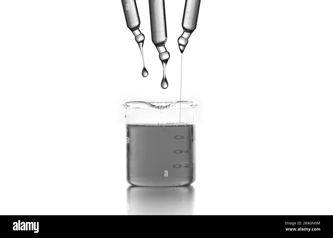 Test droppers with liquids over glass laboratory flask placed on desk