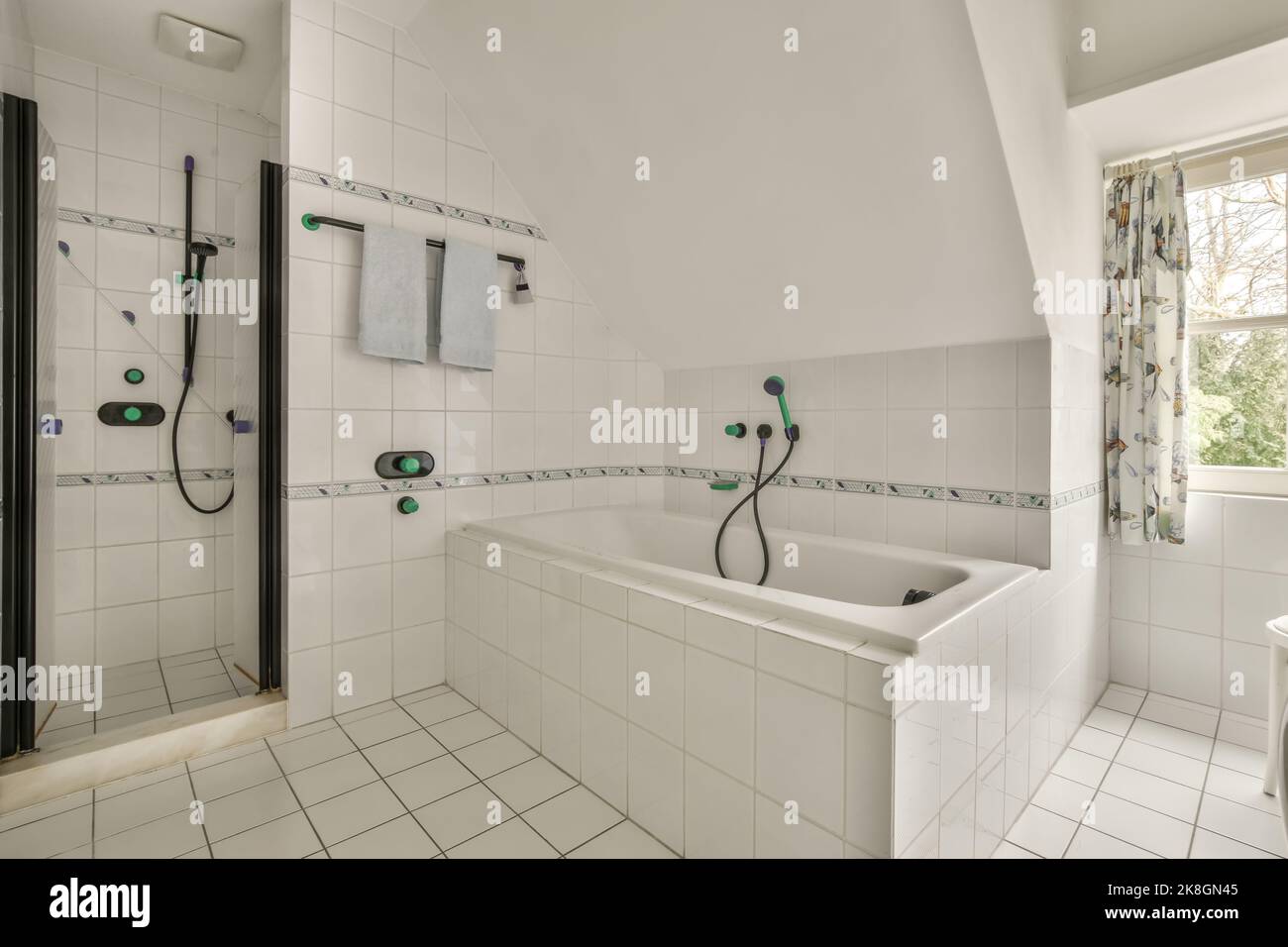 white ceramic bathtub placed near window and shower cabin in spacious