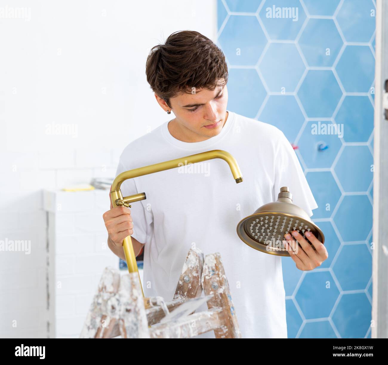 Focused guy assembling shower set before fixing to wall Stock Photo