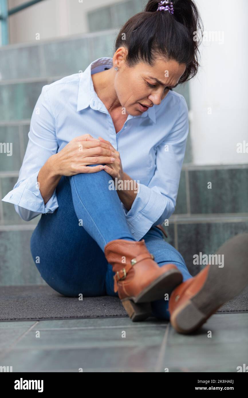 woman nursing knee after falling down stairs Stock Photo Alamy