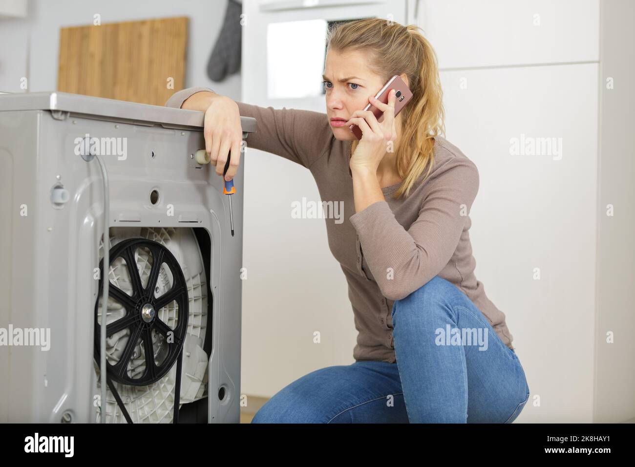 woman is calling a plumber to repair washing machine leak Stock Photo