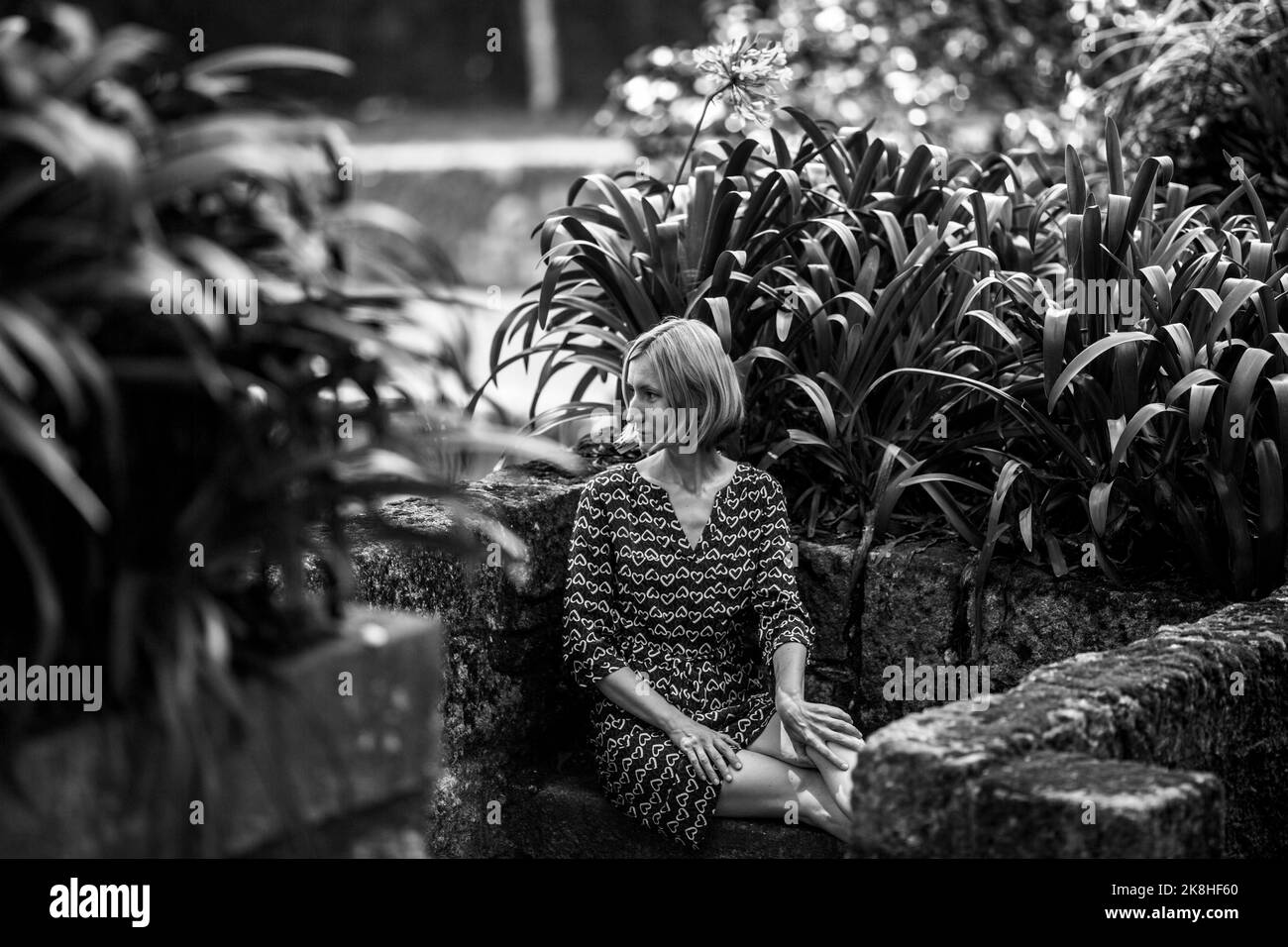 A woman on a stone bench in the ancient Park. Black and white photo. Stock Photo
