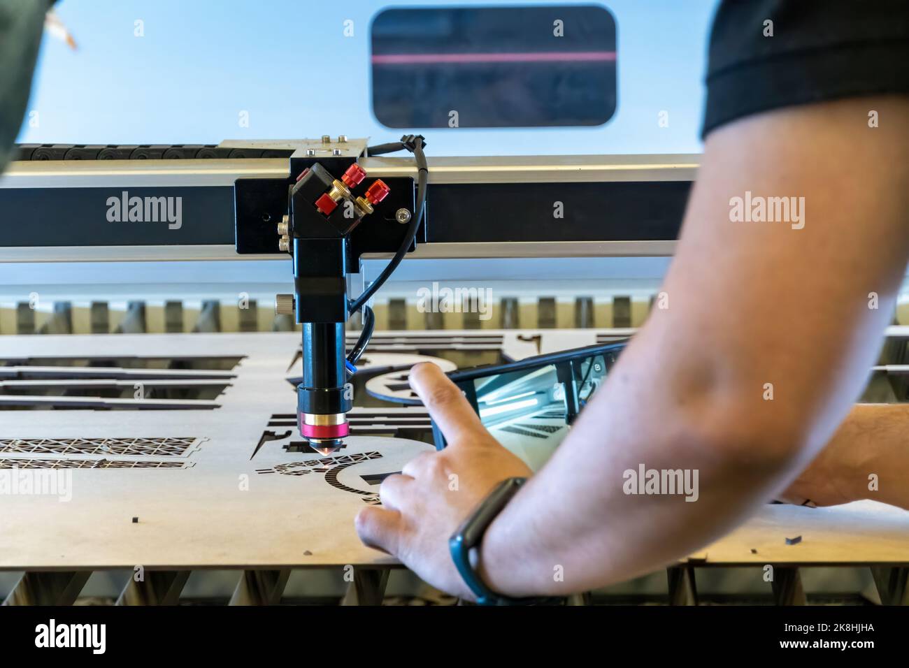 laser cutting machine, cutting wood sheets, while a man records the