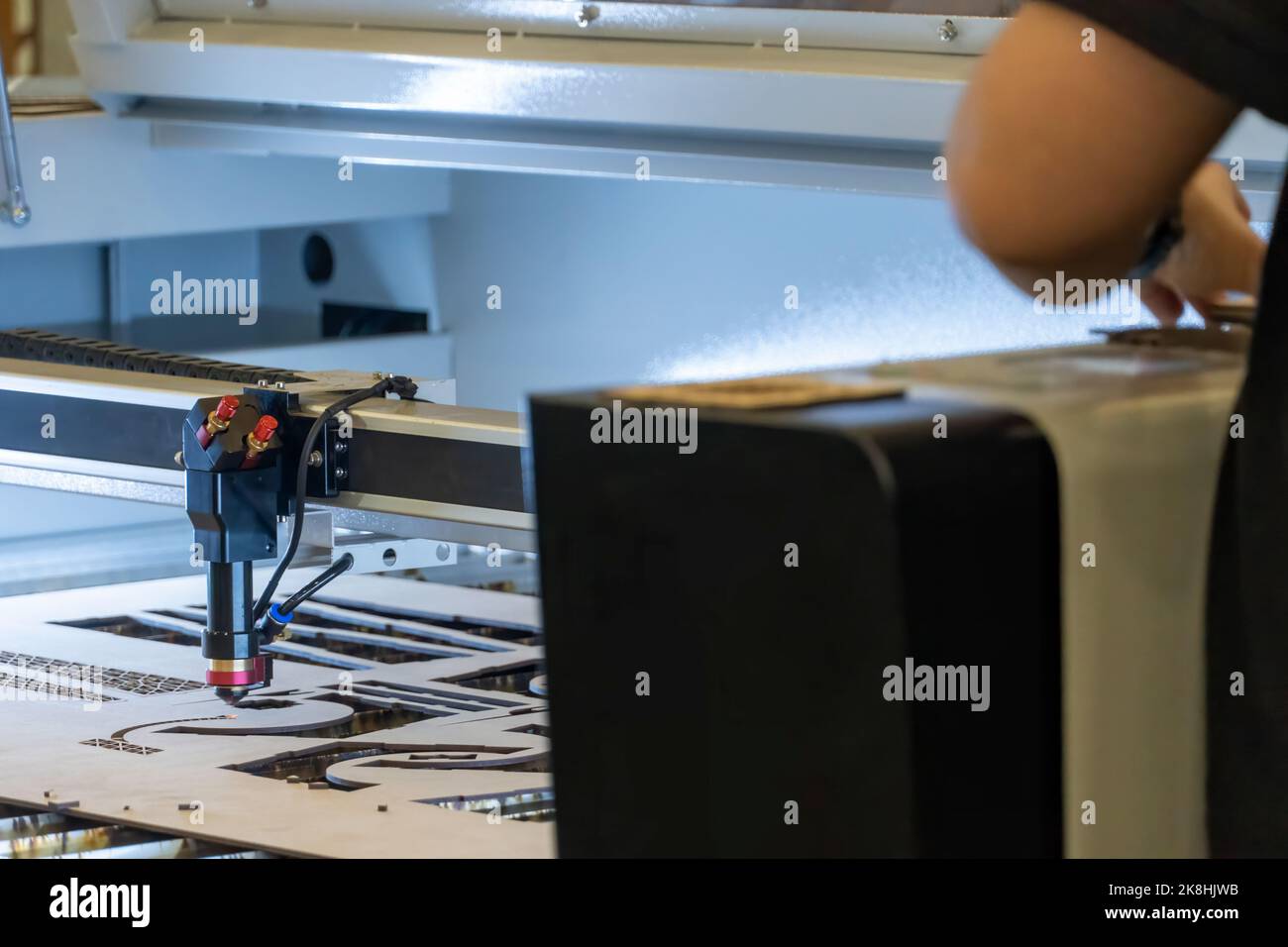 laser cutting machine, cutting wood sheets, while a man records the