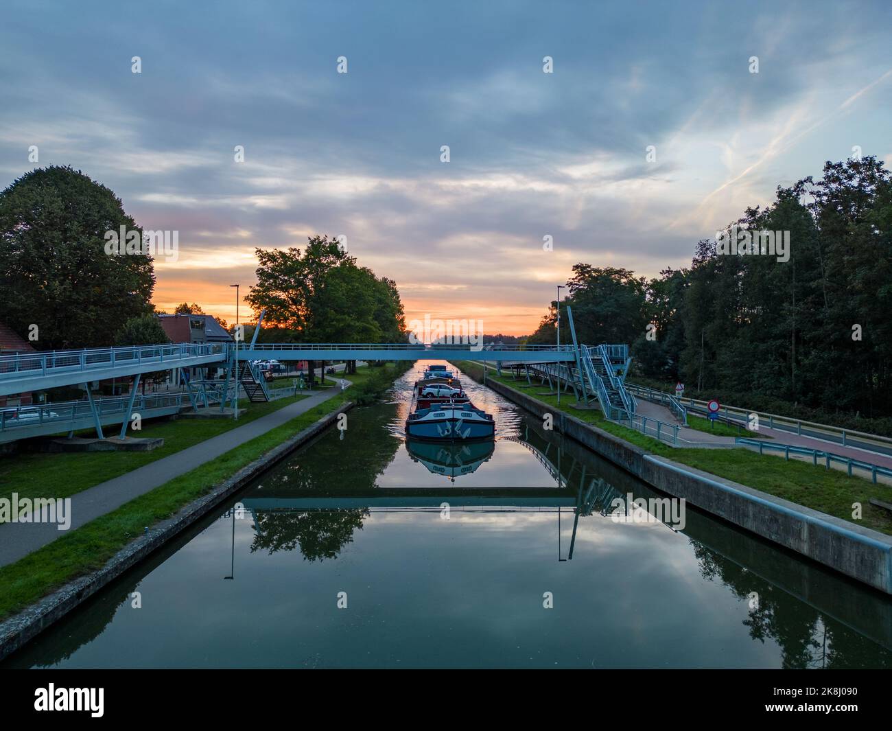 Aerial view of a colourful dramatic sunrise sky over a canal with a cargo boat in Belgium. Canals with water for transport, agriculture. Fields and me Stock Photo