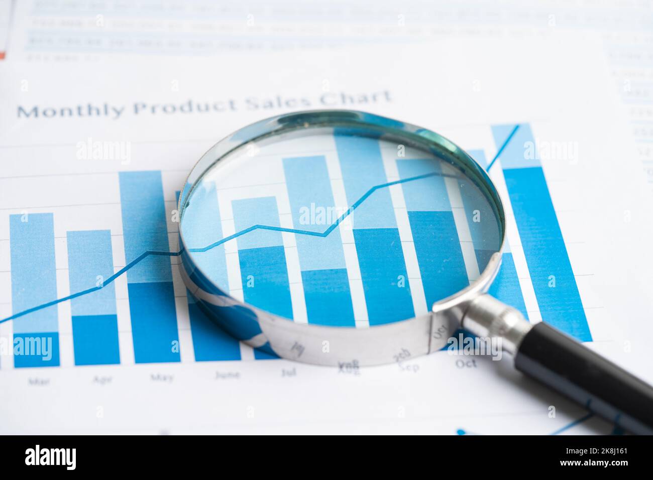 Magnifying glass on chart graph spreadsheet paper. Financial ...