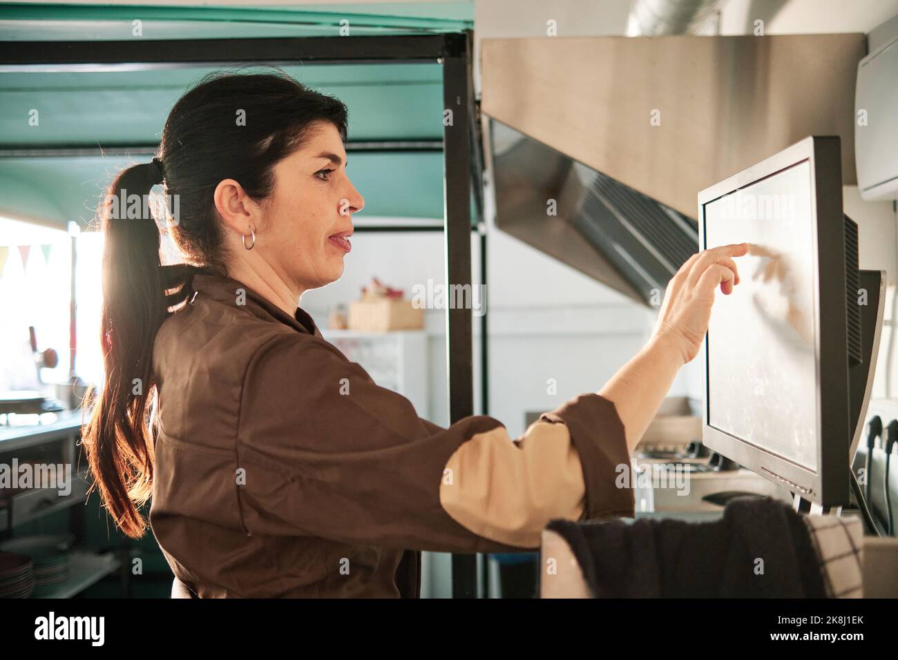 Woman checking the orders on a touch screen while working in a restaurant. Stock Photo