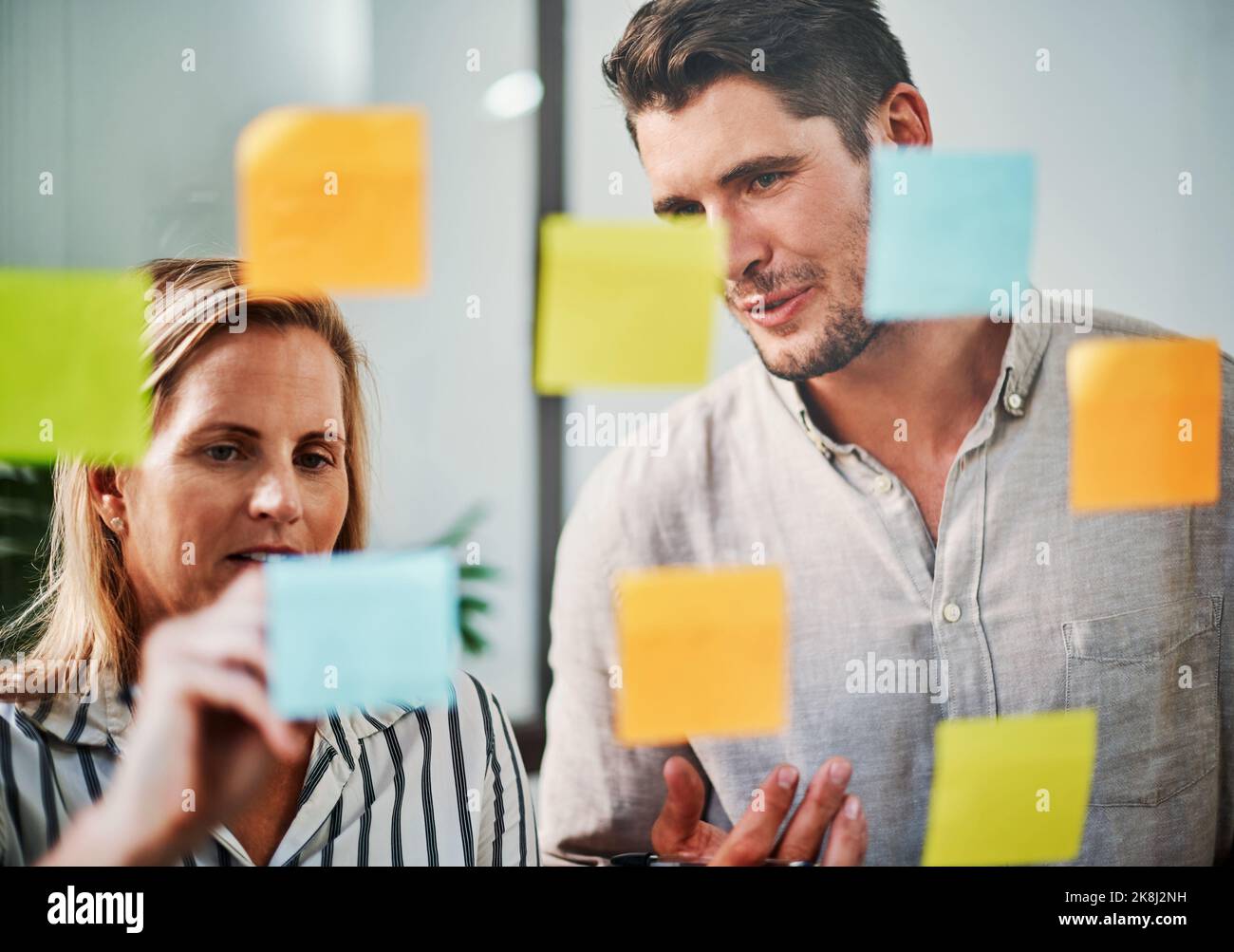 There are many ways to achieve success. two business colleagues brainstorming on a glass wipe board in their office. Stock Photo