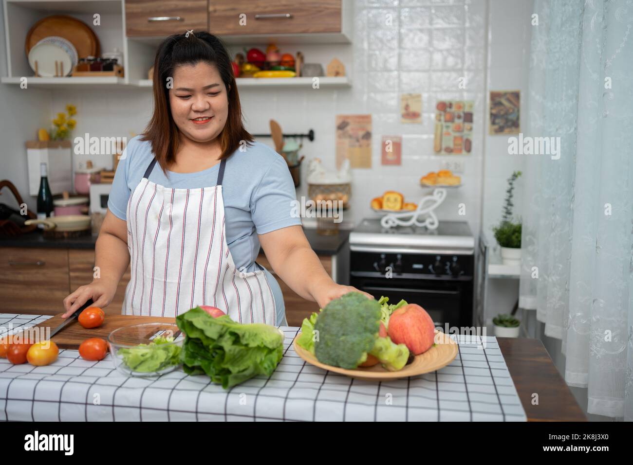 Asian Pregnant learn how to cook healthy meals from the Internet in kitchen, Fat women prepare a vegetable salad for diet food and lose weight. Concep Stock Photo