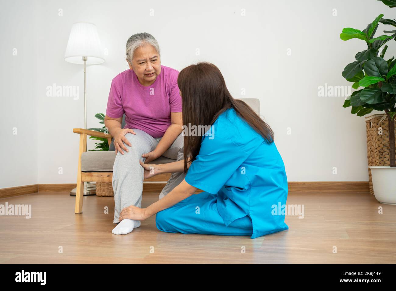 physiotherapist doctor or caregiver helping senior older woman stretching his hamstring and doing thigh or leg rehabilitation in exercise room, Osteoa Stock Photo