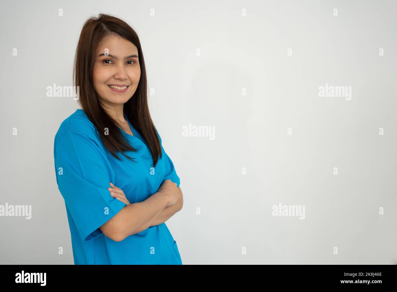 Portrait Of confident, happy, and smiling Asian medical woman doctor or nurse wearing blue scrubs uniform over isolated white background Stock Photo